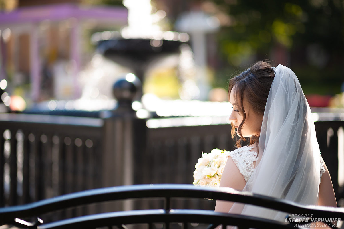 невеста сидит на скамейке возле фонтана