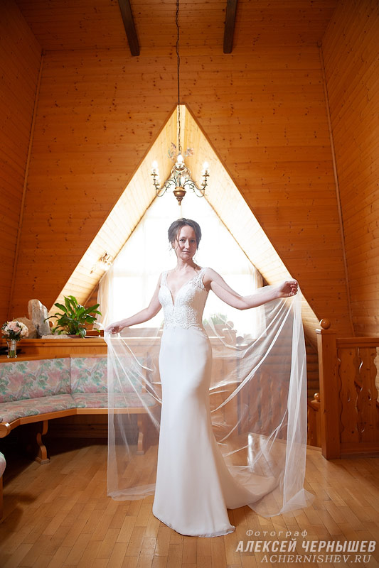 невеста с длинной фатой в деревянном доме