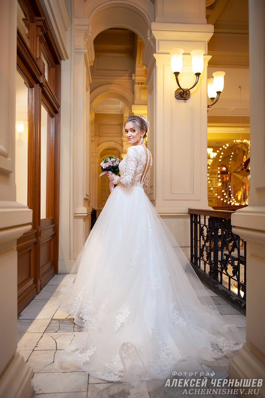 Свадебная фотосессия в ГУМе - фото невеста показывает шлейф своего платья