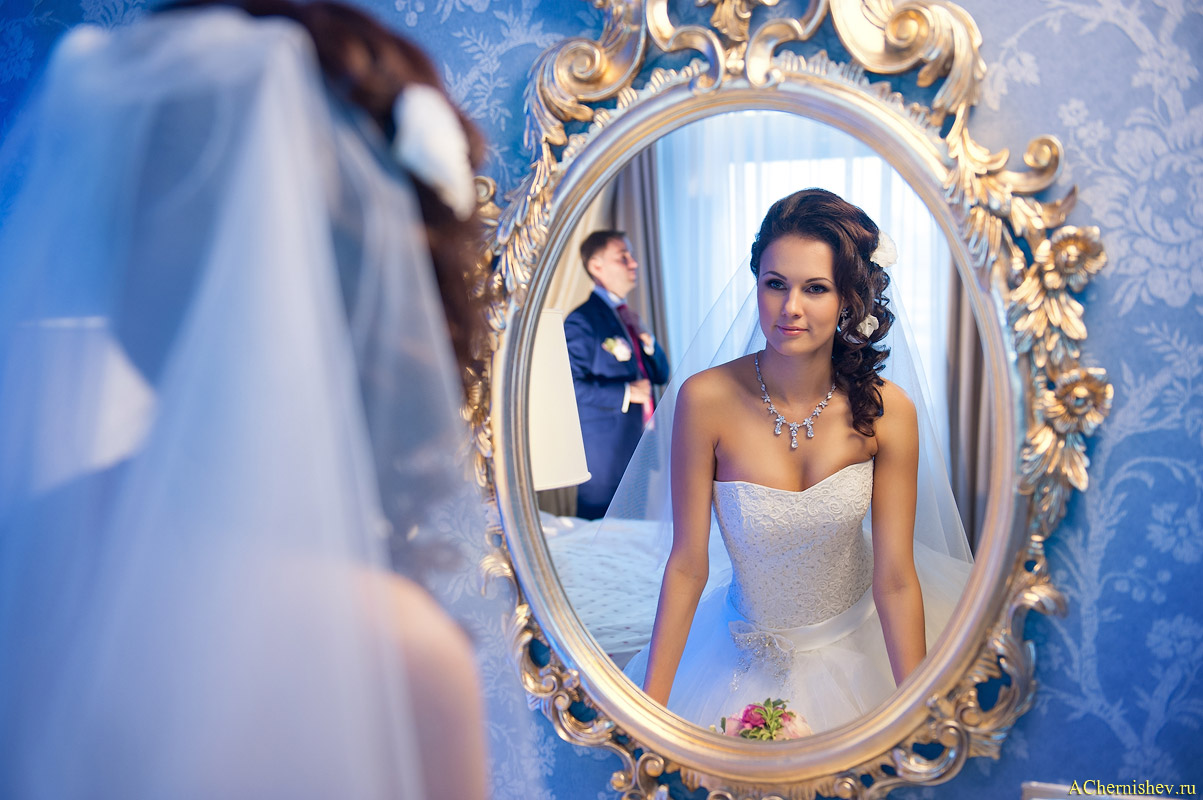 утро невесты у зеркала, на заднем плане жених