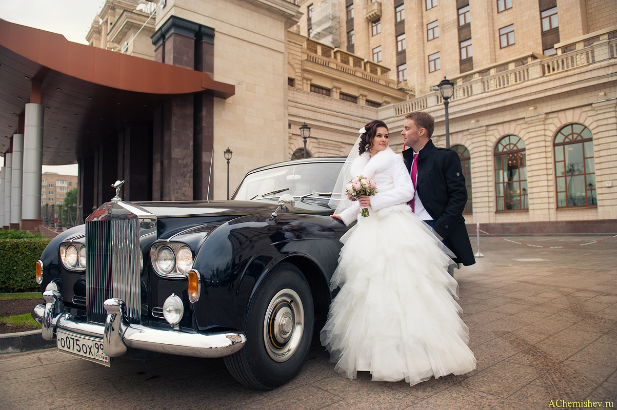 жених и невеста с ретро автомобилем у фасада отеля Редиссон (бывшая Украина)
